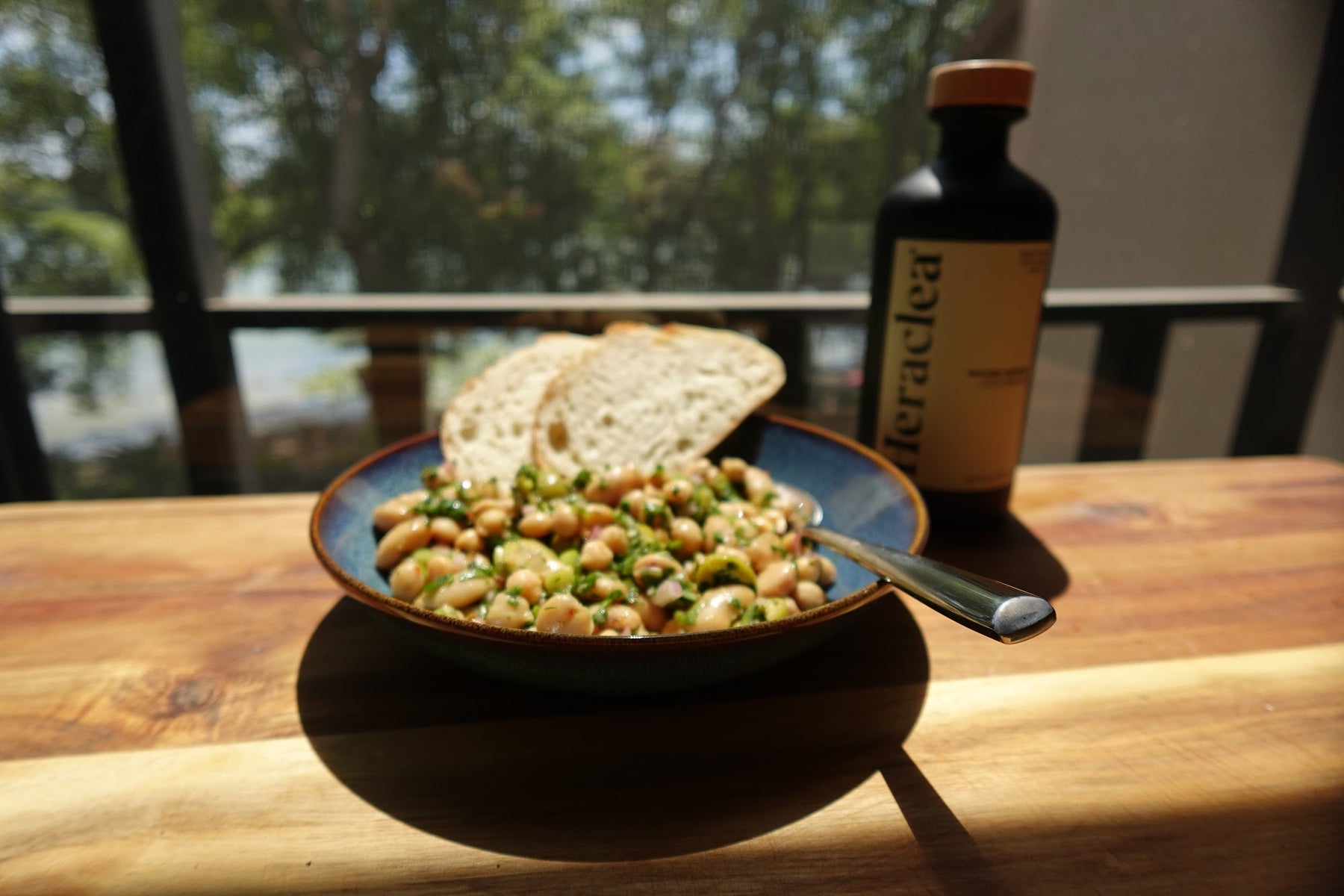 Bean salad with chickpeas, butter beans, halved Castelvetrano olives, and fresh mint and parsley in a serving bowl