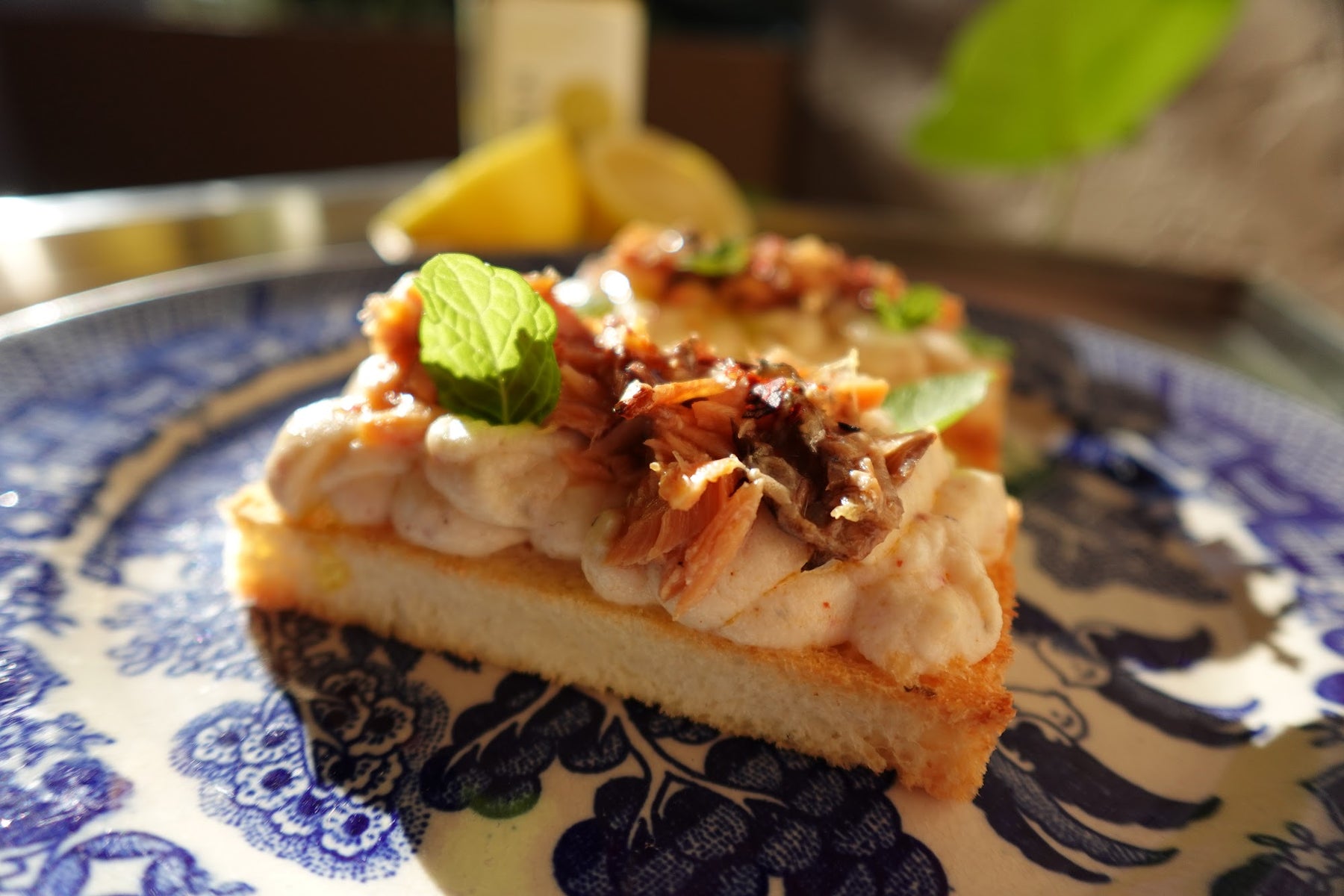 Smoked salmon appetizer crostini on milk bread with whipped lemon-olive oil ricotta, fresh herbs, and Aleppo pepper