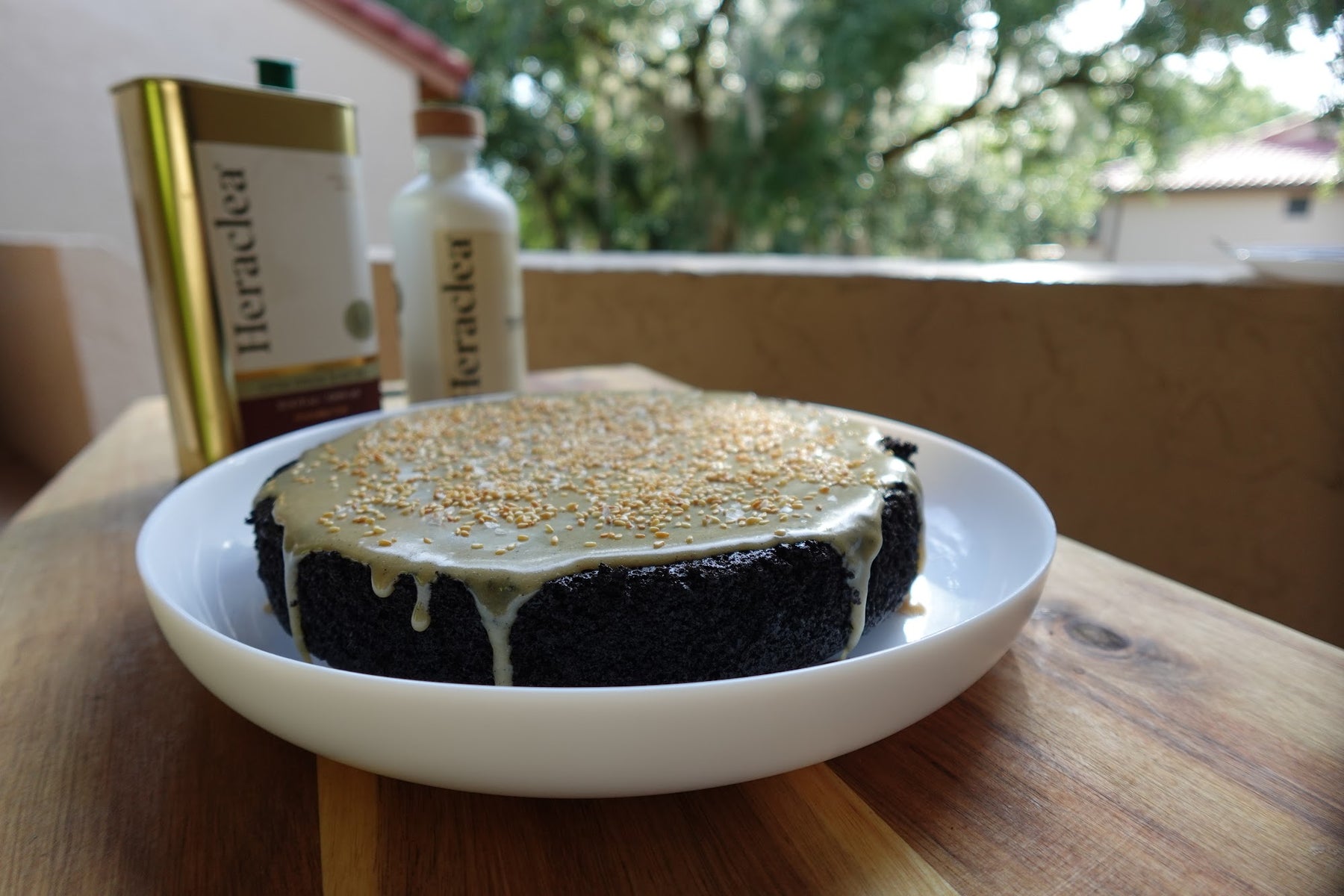 Chocolate olive oil cake glazed with tahini olive oil glaze and scattered with toasted sesame seeds